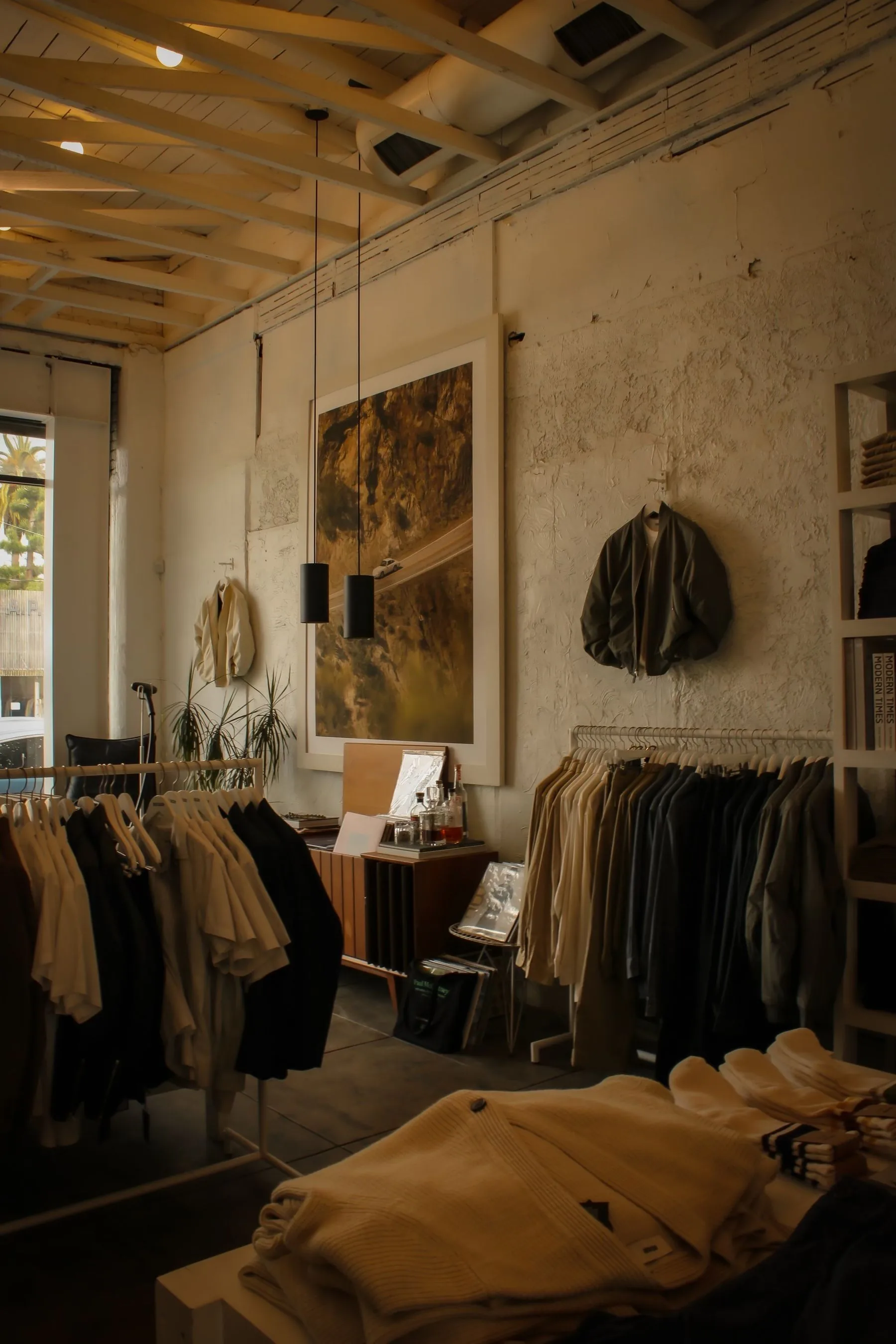 A warm, quietly arranged clothing studio with garments selected on timber rails